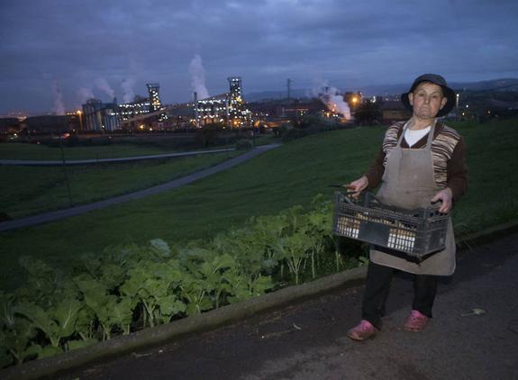 Chelo López con una caja de patatas que guarda en el hórreo de su casa, frente a Arcelor. 