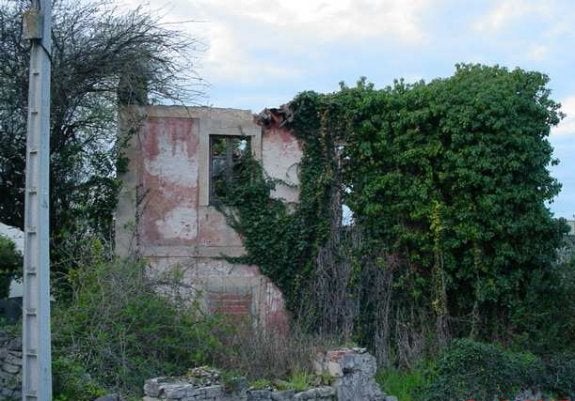 La antigua escuela de Roces, en ruinas y cubierta de maleza. 