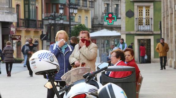 Dos mujeres se protegen del gas en Avilés. 