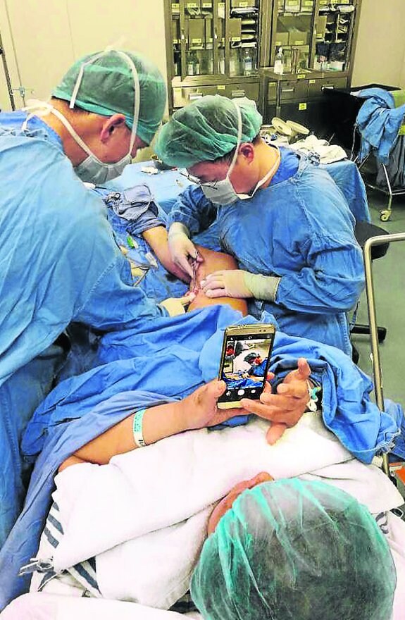 Zhu, de 69 años, toma imágenes de la operación, mientras otra persona la fotografía a ella. 