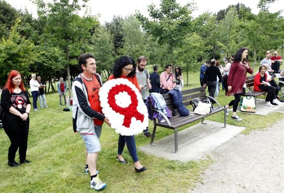 Vanessa Gutiérrez y un voluntario llevan la ofrenda floral en el memorial en Los Pericones. 