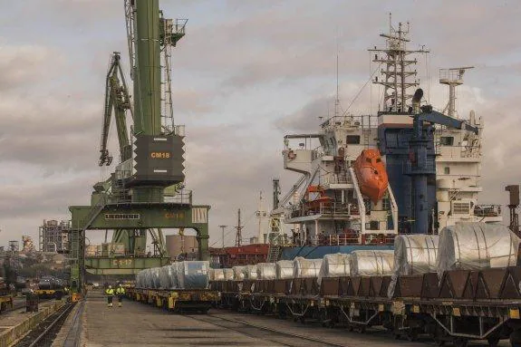 Bobinas producidas por la fábrica de Ilva (al fondo), en el puerto de Tarento a la espera de ser cargadas en barcos. 