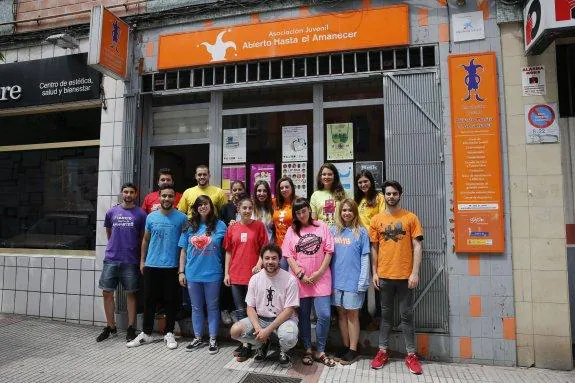 El actual equipo de Abierto Hasta el Amanecer, posando con las camisetas históricas de la asociación frente a su local de trabajo. En el centro, de naranja, la presidenta Lucía García con la nueva camiseta de este año. 