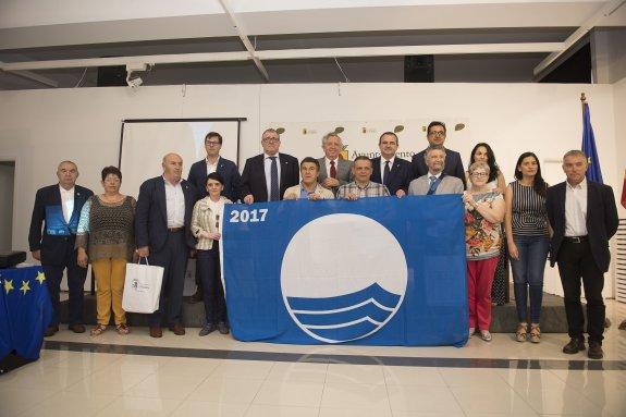 Representantes de los concejos galardonados y autoridades, en Luarca, con una bandera azul. 