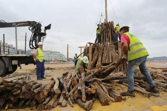 Varios operarios, ayer, durante el levantamiento de la hoguera en la playa de Poniente. 