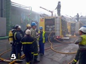 Dotaciones de bomberos que intervinieron en el incendio lanzan agua contra las instalaciones afectadas por el fuego. ::                             BOMBEROS DE ASTURIAS