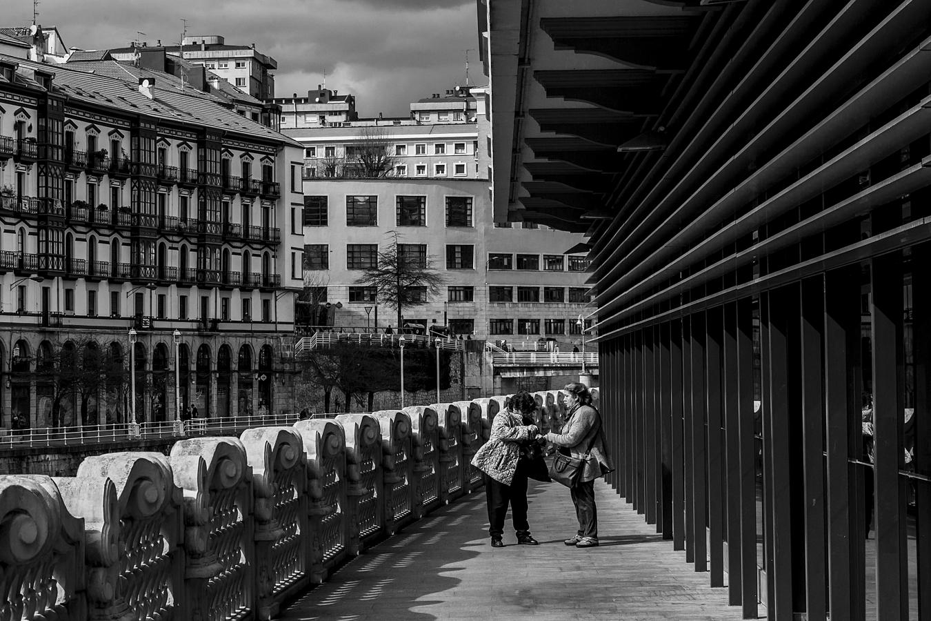 Dos mujeres hacen un alto junto a la ría, al lado del mercado de la Ribera.