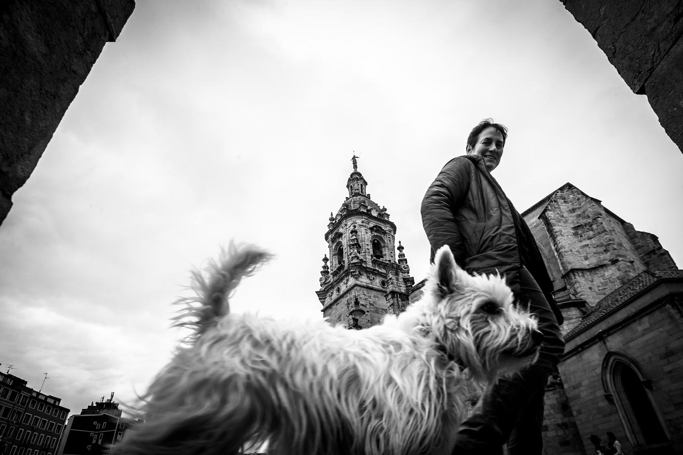 Una señora pasea con su perro junto a la iglesia de San Antón.
