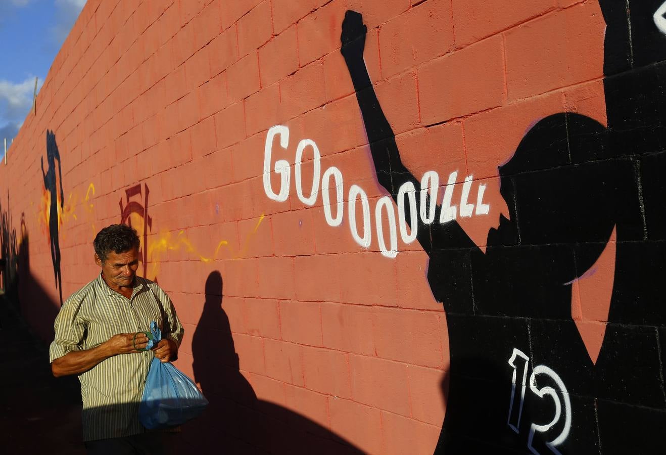 Un hombre pasa junto a una pared pintada cerca de la entrada del estadio Estadio Manoel Barradas en la ciudad Salvador de Bahía