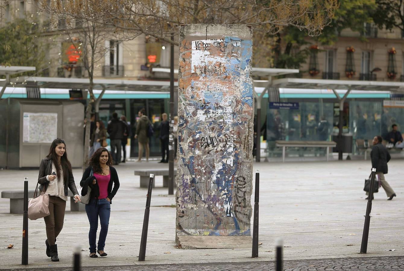 Dos jóvenes pasan junto al fragmento del Muro de Berlín que se encuentra en la Puerta de Versalles, en París.