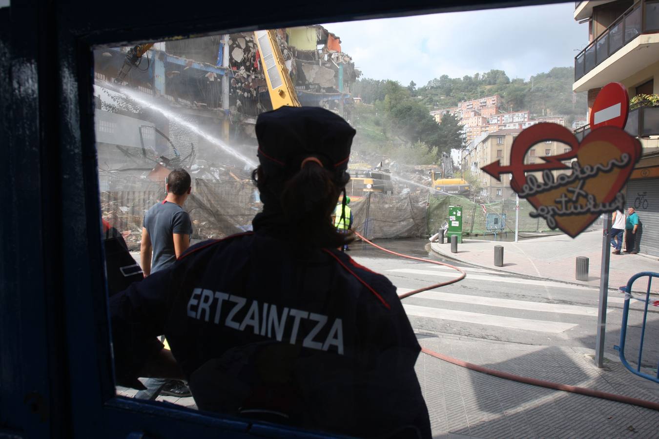 Un agente de la Ertzaintza supervisa las labores de derribo.