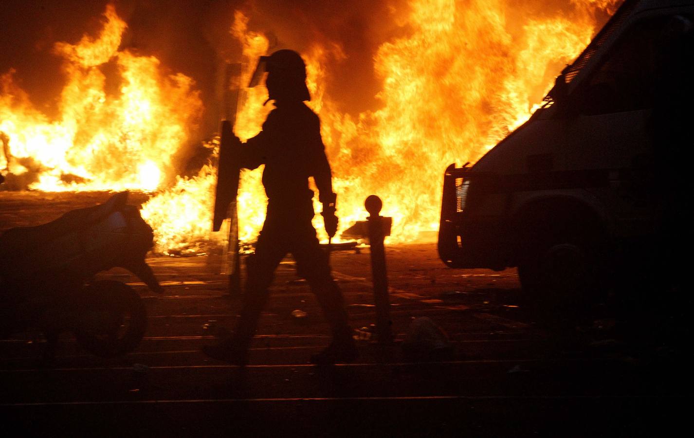 Silueta de un ertzaina frente a las llamas provocadas por el incendio de varios contenedor en las calles de Bilbao por el derribo de Kukutza en septiembre de 2011-