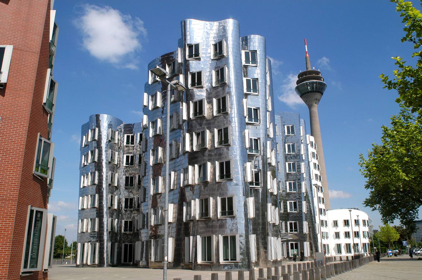 Neuer Zollhof, Düsseldorf (Alemania). Levantado en octubre de 1999, se trata de un complejo arquitectónico conformado por tres edificios, cada uno con una fachada diferente. Si el espectador se sitúa de espaldas al Rin, a la izquierda verá un bloque de yeso blanco, y la derecha del todo otro de ladrillo rojo. En medio, el de la imagen, con paredes de aluminio. Todos comparten el estilo ondulante tan característico de Gehry.