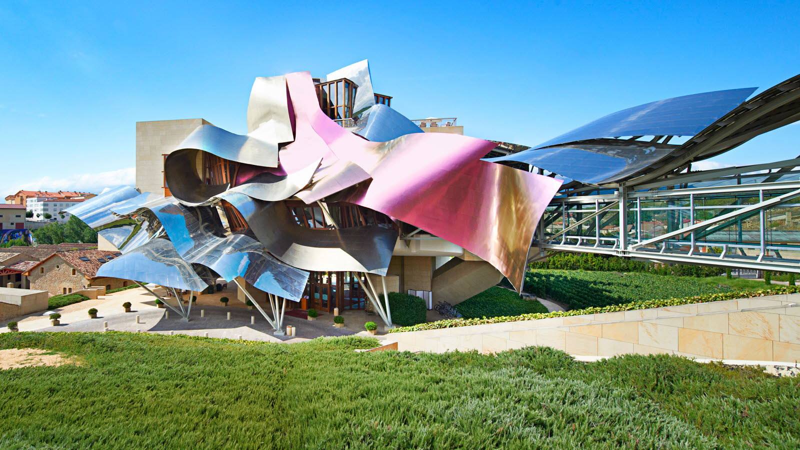 Bodega Marqués de Riscal, La Rioja. Marqués de Riscal es la bodega más antigua y tradicional de la Rioja, pero cuenta con el edificio más vanguardista de la comunidad autónoma. Los tonos que reflejan el aluminio de su fachada recuerdan al rojo del vino tinto, al dorado de la malla y al plateado de la cápsula de la botella de vino de la casa riojana. Las paredes de piedra son del mismo color que la arenisca que se utilizaba en la arquitectura tradicional de la zona.