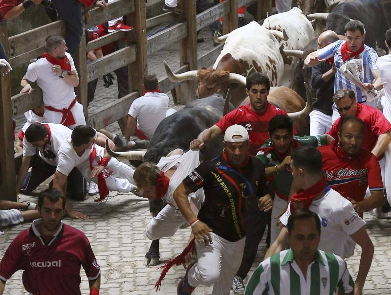 Los mosos son alcanzados por los toros durante el encierro.