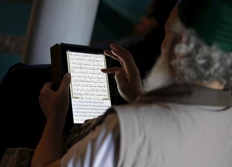 Un devoto musulmán lee el Corán en árabe y alemán en su tablet durante las oraciones en la mezquita Sehitlik en Berlín, Alemania