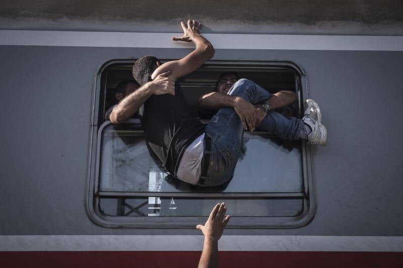 La fotografía muestra a un inmigrante luchando por subir a un tren, en Zagreb (Croacia). Serie ganadora de Noticias de Actualidad.