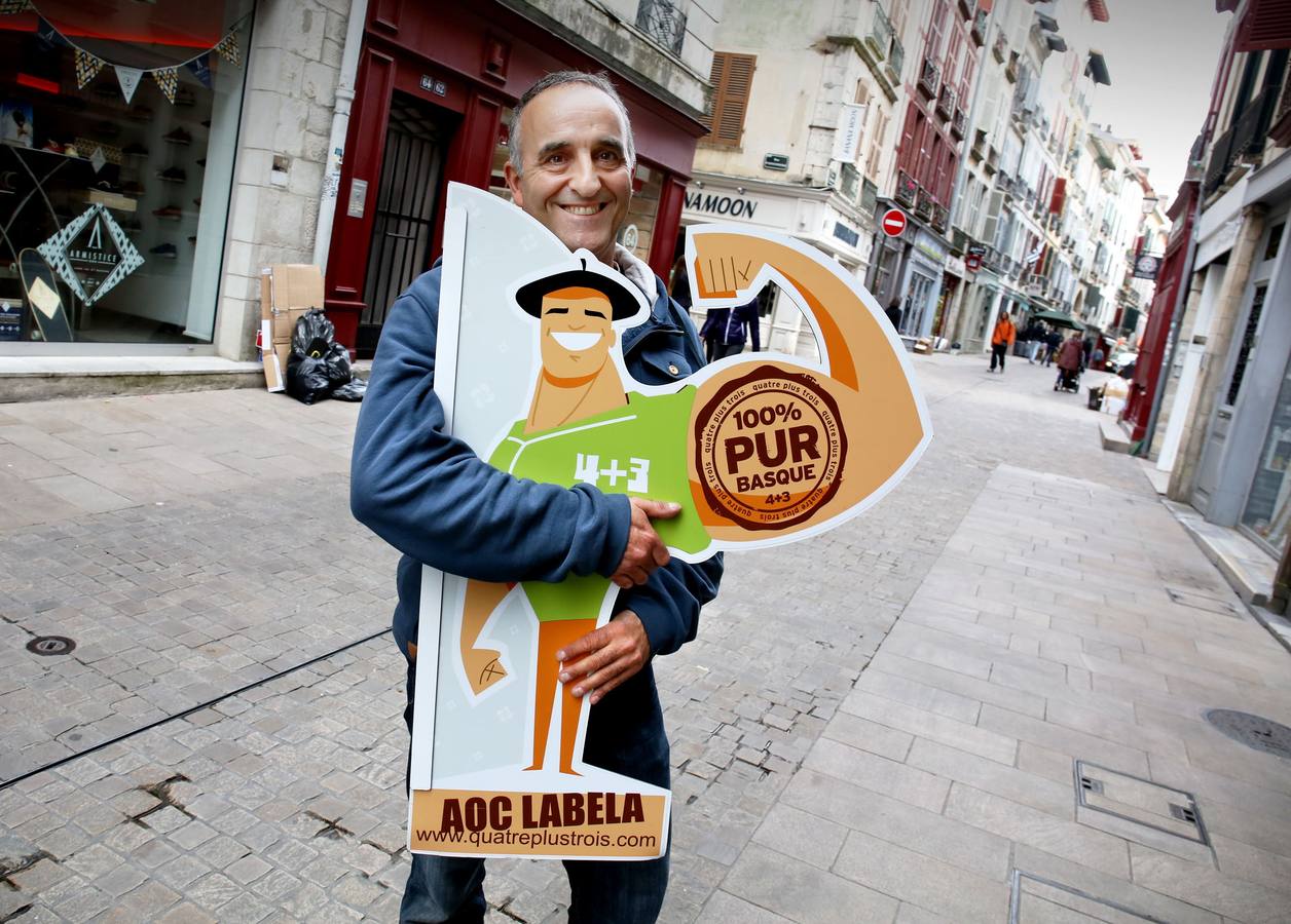 Bertrand Barbaste, gestor de la tienda de ropa Quatre+Trois en la rue d'Espagne, una de las calles más turísticas de la parte vieja de Bayona, sostiene un cartel de su establecimiento.