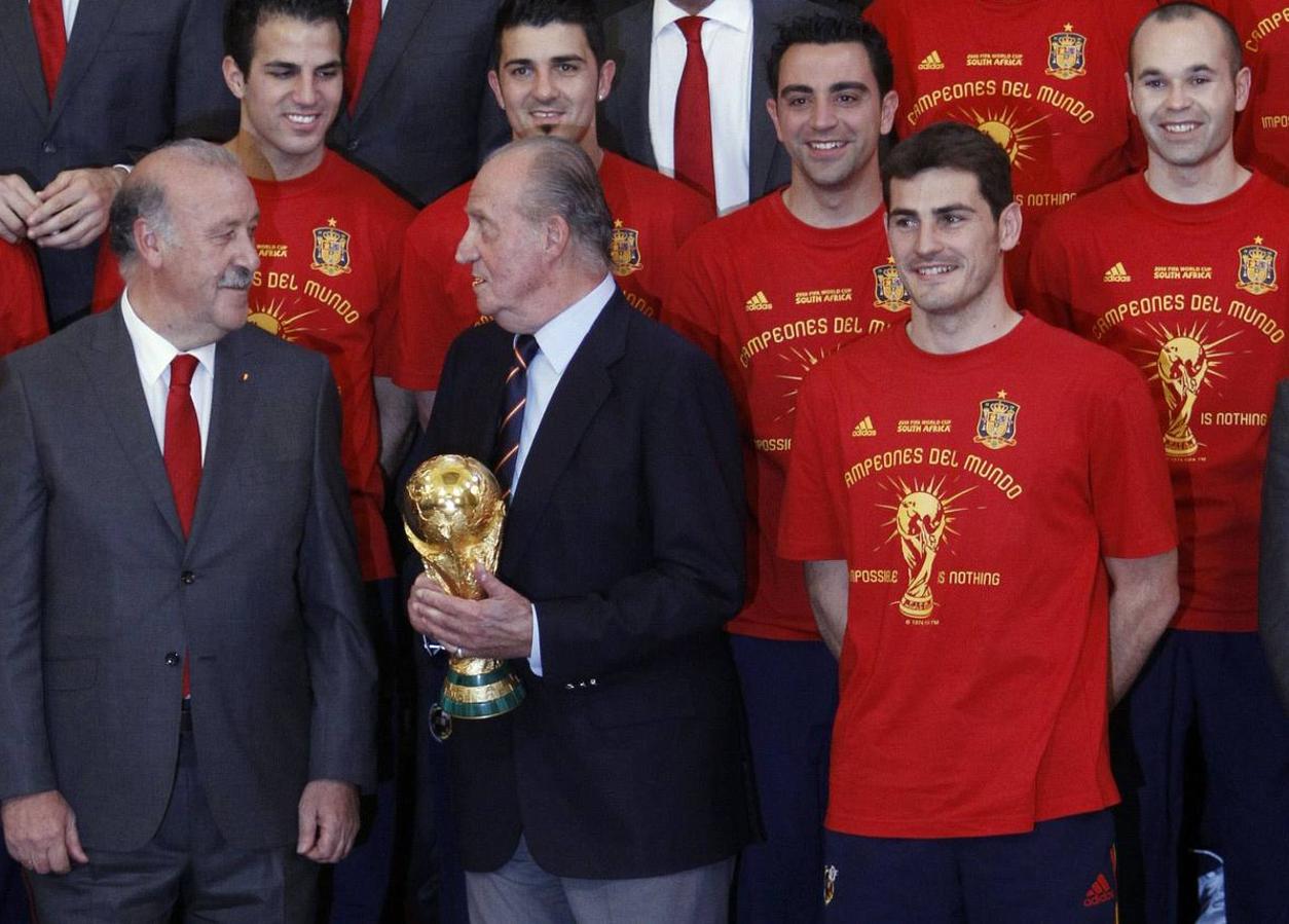 12 de julio de 2010. El Rey Juan Carlos sostiene el trofeo de la Copa Mundial mientras posa entre el entrenador y el capitán Casillas durante una recepción en el Palacio Real de Madrid.