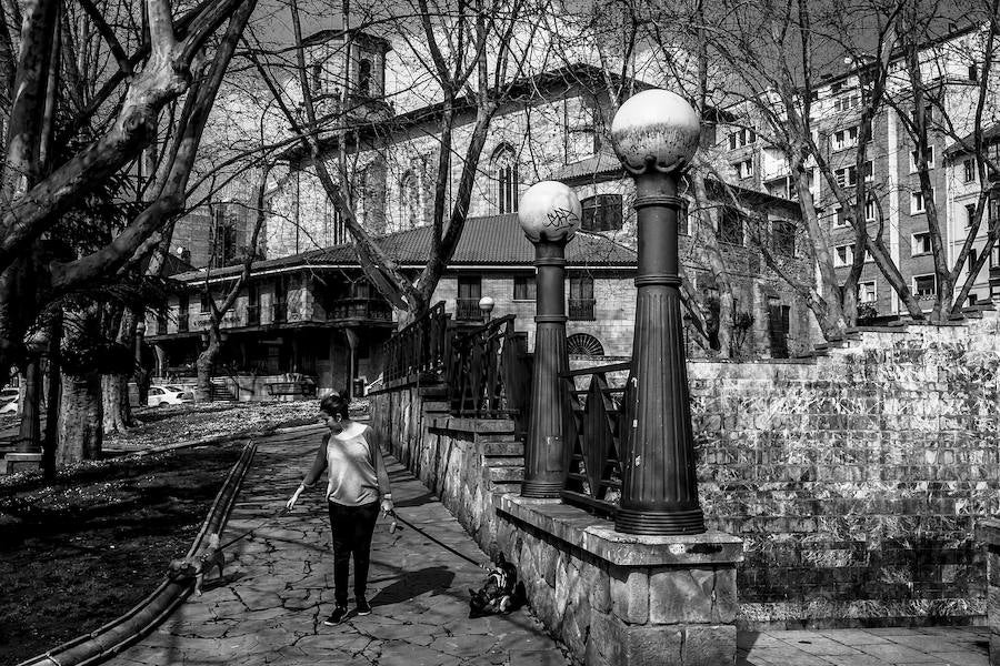 Una mujer pasea a su perro junto a la parroquia de San Pedro Apóstol.