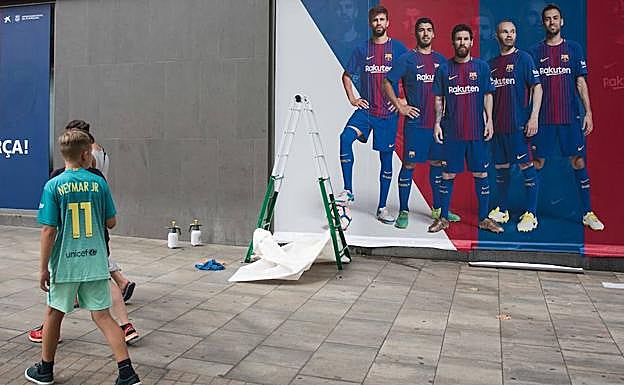 Un niño con la camiseta de Neymar contempla un póster en el exterior del Camp Nou en el que ya no hay rastro del brasileño. 