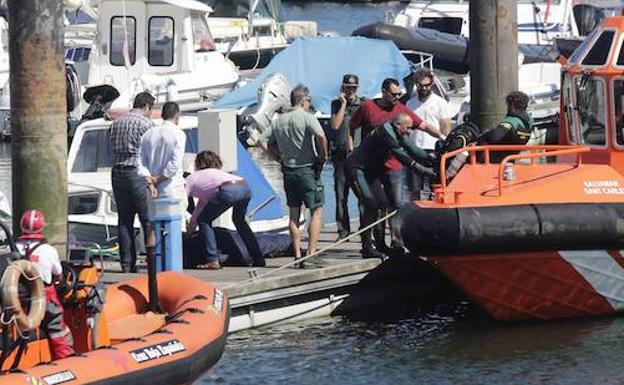 Efectivos de la Guardia Civil desembarcan en el puerto el cuerpo del submarinista fallecido.