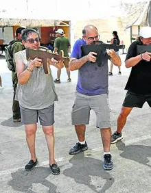 Imagen secundaria 2 - 1. Los asistentes al cursillo atienden las explicaciones de uno de los monitores. 2. Los clientes se agazapan tras un instructor armado.3. Antes de usar fuego real se ejercita con metralletas de madera. 