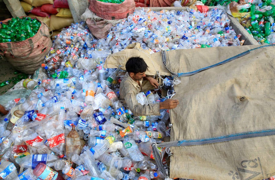 Operarios se abren paso entre montañas de botellas en una de las plantas de reciclaje de la capital de Pakistán