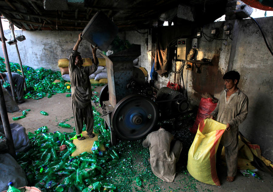Operarios se abren paso entre montañas de botellas en una de las plantas de reciclaje de la capital de Pakistán