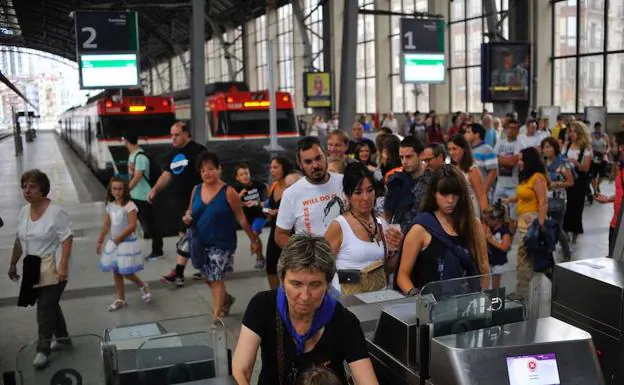 Viajeros de Cercanías de Renfe validan sus bitteltes en las canceladoras.