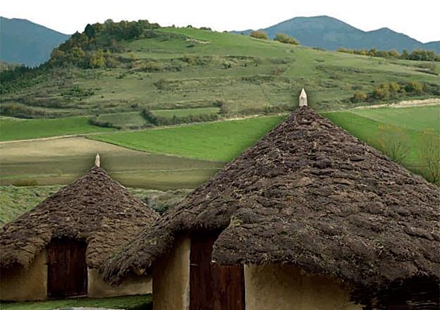 Las dos viviendas reconstruidas en el centro de interpretación, con el Castro de Henayo al fondo.