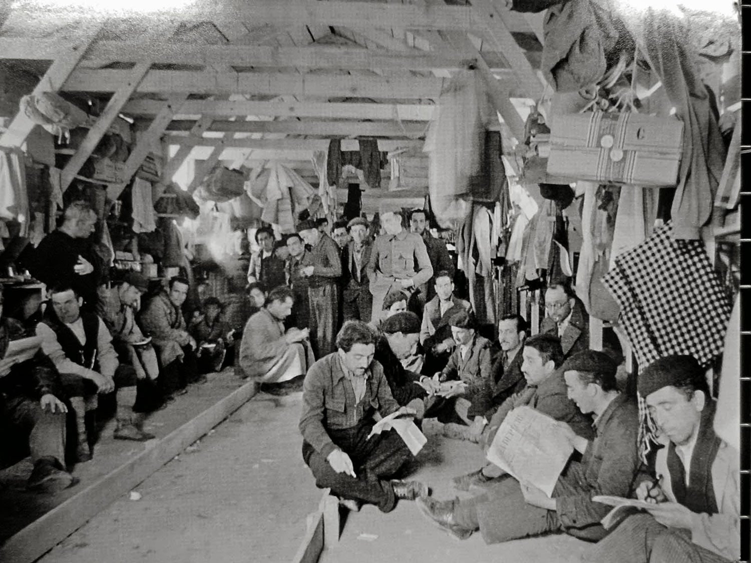 Interior de uno de los barracones de Gurs, donde un grupo de reclusos aparece leyendo.