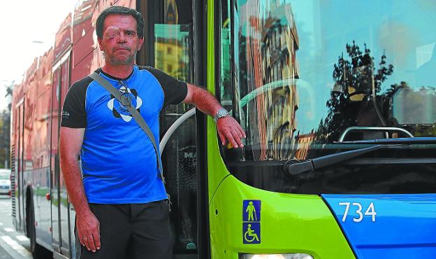 Xabier Arzelus,con un ojo vendado tras la agresión, posa en Intxaurrondo junto a un autobús como el que conduce a diario.