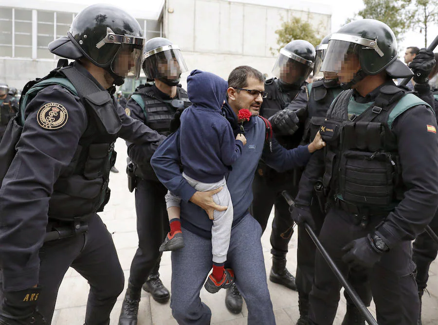 Agentes de la Guardia Civil tratan de desalojar de un colegio a un padre acompañado de su hijo.