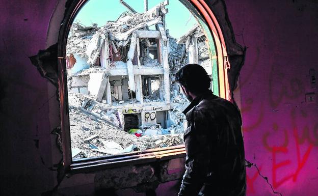 Un miembro de las Fuerzas de Siria Democrática observa desde una ventana las secuelas de la lucha contra el El en Raqqa.