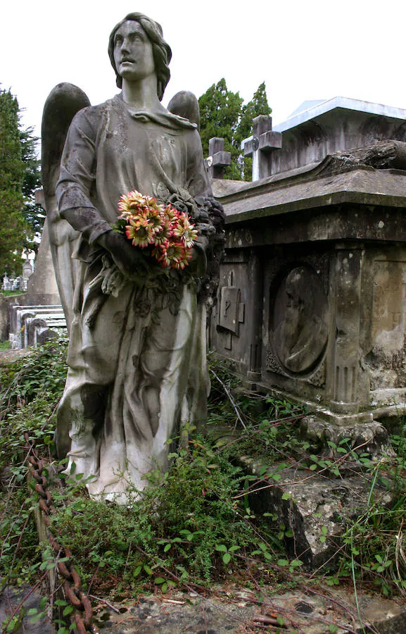 Un ángel sostiene un ramo de flores frescas en el cementerio de Derio.