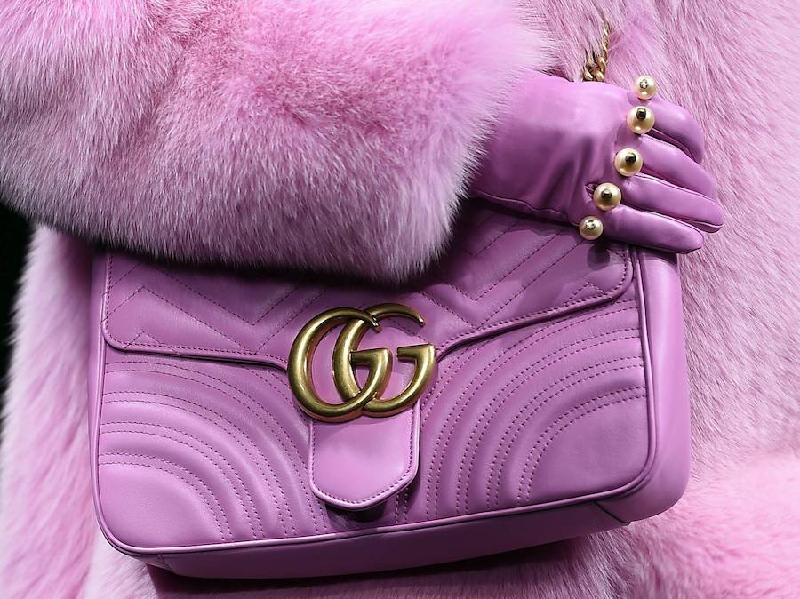 Una modelo desfila para Gucci con una abrigo de pelo y un bolso de piel rosas.