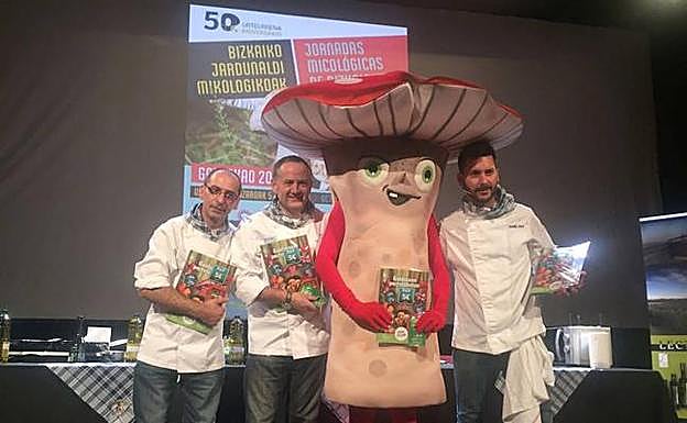 Cocineros y la mascota de las jornadas sostienen el álbum. 