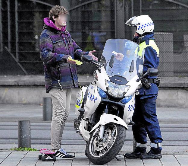 Un agente sanciona a un joven que circulaba en patinete.