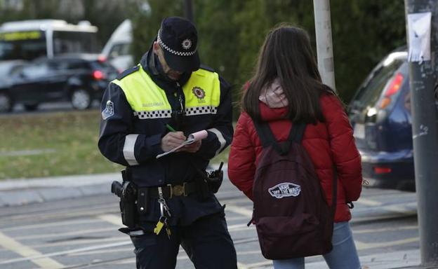 Un policía local de Vitoria impone una sanción a una adolescente, ayer en la calle Magdalena. 