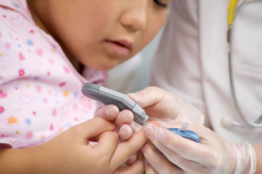 Un médico mide el nivel de glucosa a una niña.