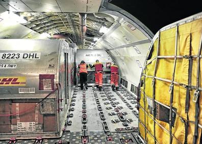 Imagen secundaria 1 - Arriba, el ritmo de trabajo es intenso en las cuatro horas que concentran la entrada y salida de los aviones. En segundo lugar, arrastre y sujeción de cada posición en el interior del Airbus. En la tercera imagen vemos a Acron, cuyo olfato ha permitido detectar contenidos ‘opacos’.