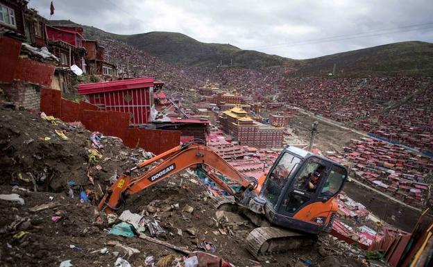 Una excavadora derriba una barriada de chabolas en el extrarradio de una ciudad china.
