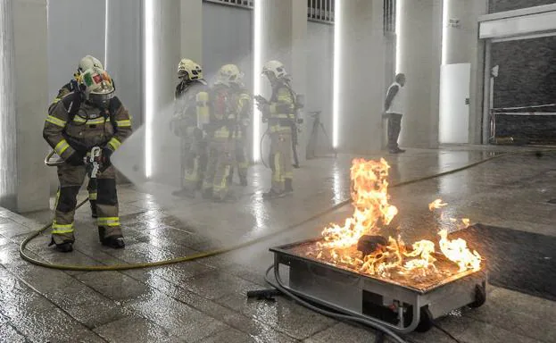 Un bombero apaga uno de los fuegos prendidos para el simulacro de incendio. 