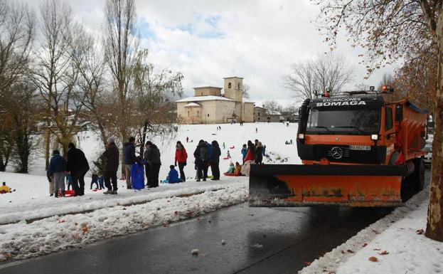 Un camión quitanieves pasa por unas campas de Armentia llenas de gente que disfruta de la nieve. 