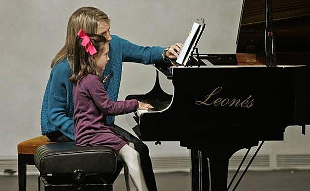 Una niña aprende a tocar el piano.