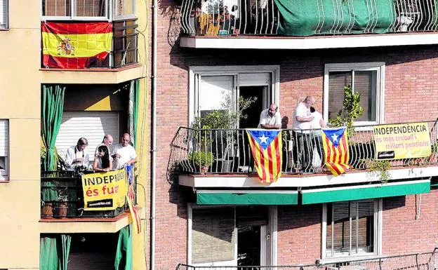 Vecinos de Barcelona se asoman a sus balcones, engalanados con esteladas y pancartas independentistas. En otro luce una española