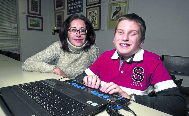 Álvaro, junto a su madre, utiliza una línea braille para 'ver' toda la información a que le da acceso su ordenador.