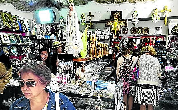 En busca de ‘souvenirs’. Un grupo de turistas revisan los estantes de una tienda de recuerdos religiosos ubicada en Borgo Pío.