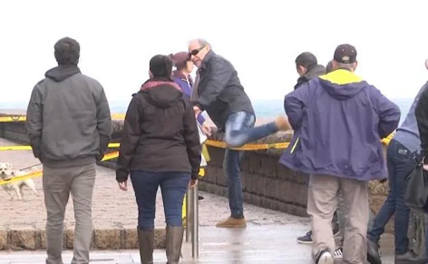 Un grupo de personas cruza la valla de prohibición para ver las olas en directo en el Paseo Nuevo.